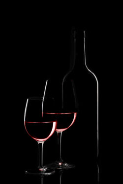 Red wine bottle and two wine glasses on black background