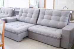 Gray tufted sectional sofa with matching cushions in a showroom setting.